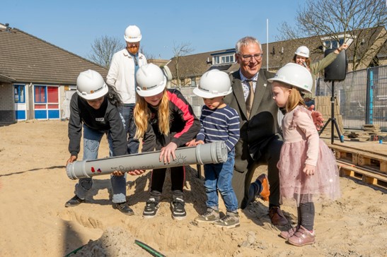 Op de foto zie je 4 leerlingen en wethouder Herman Romeijn die een tijdscapsule in de grond leggen