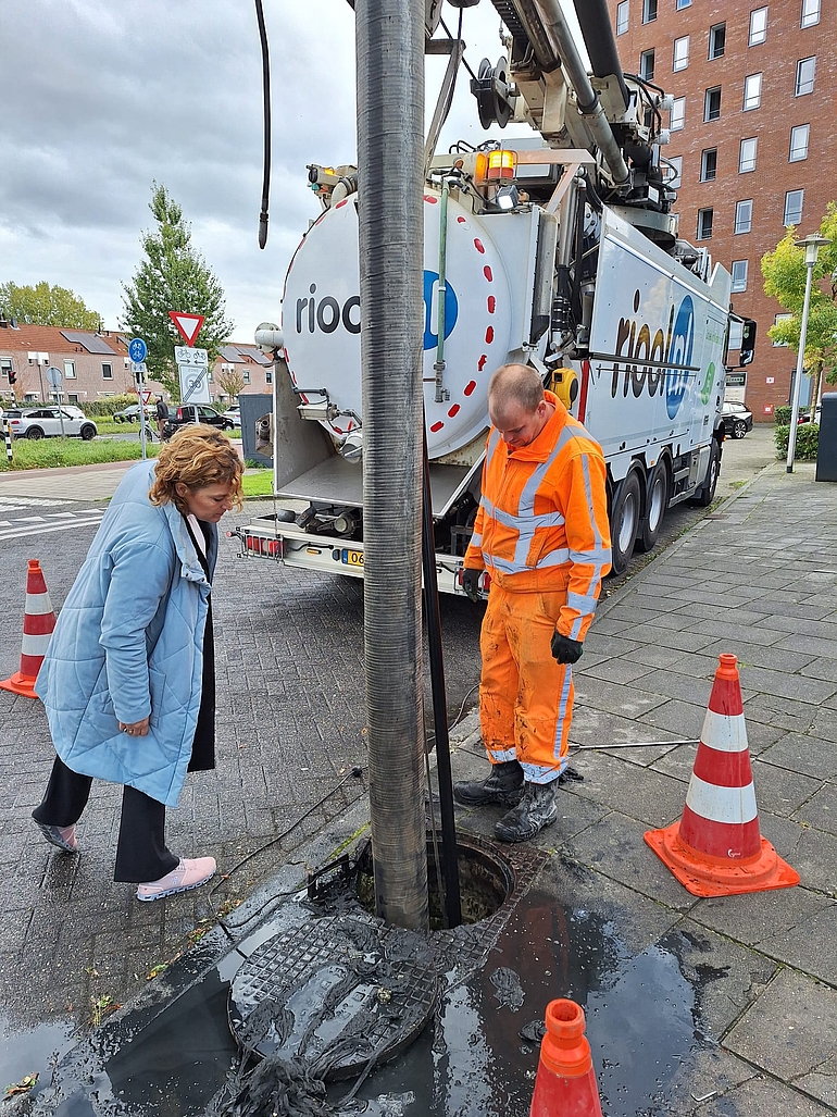 Wethouder van Gaal en rioolinspecteur die het riool schoonmaken