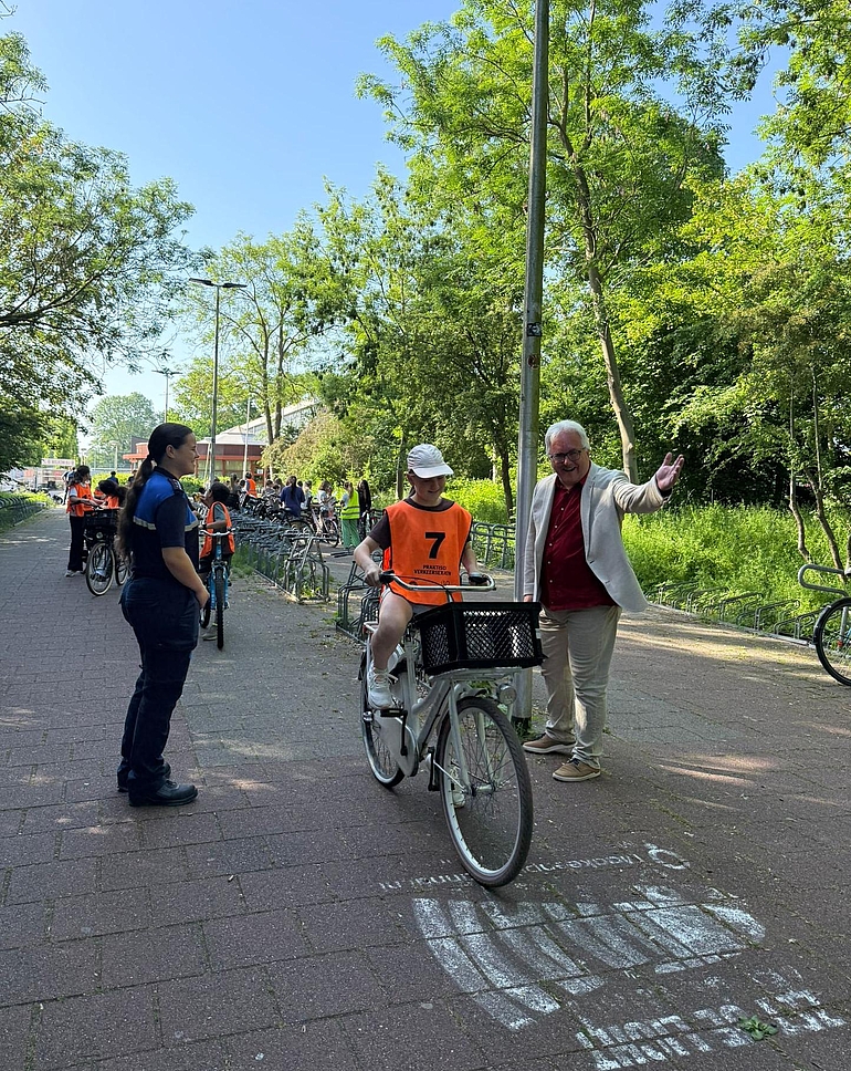 Foto praktijkverkeersexamen met fietsende scholier, wethouder Blommers en boa