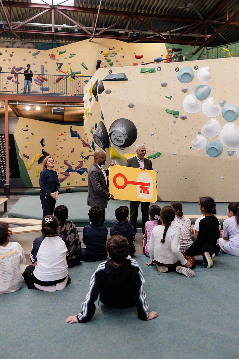 Wethouders Jermoum (links) en Romeijn (rechts) houden logo van de Sleutelpas vast