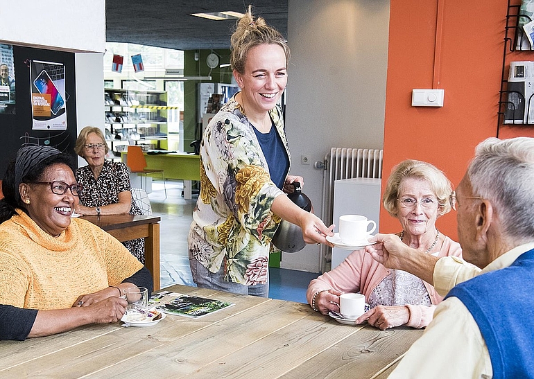 Verschillende mensen aan tafel die thee drinken