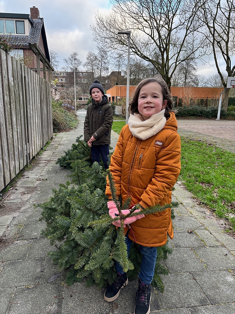 Foto van kinderen die buiten met een kerstboom slepen